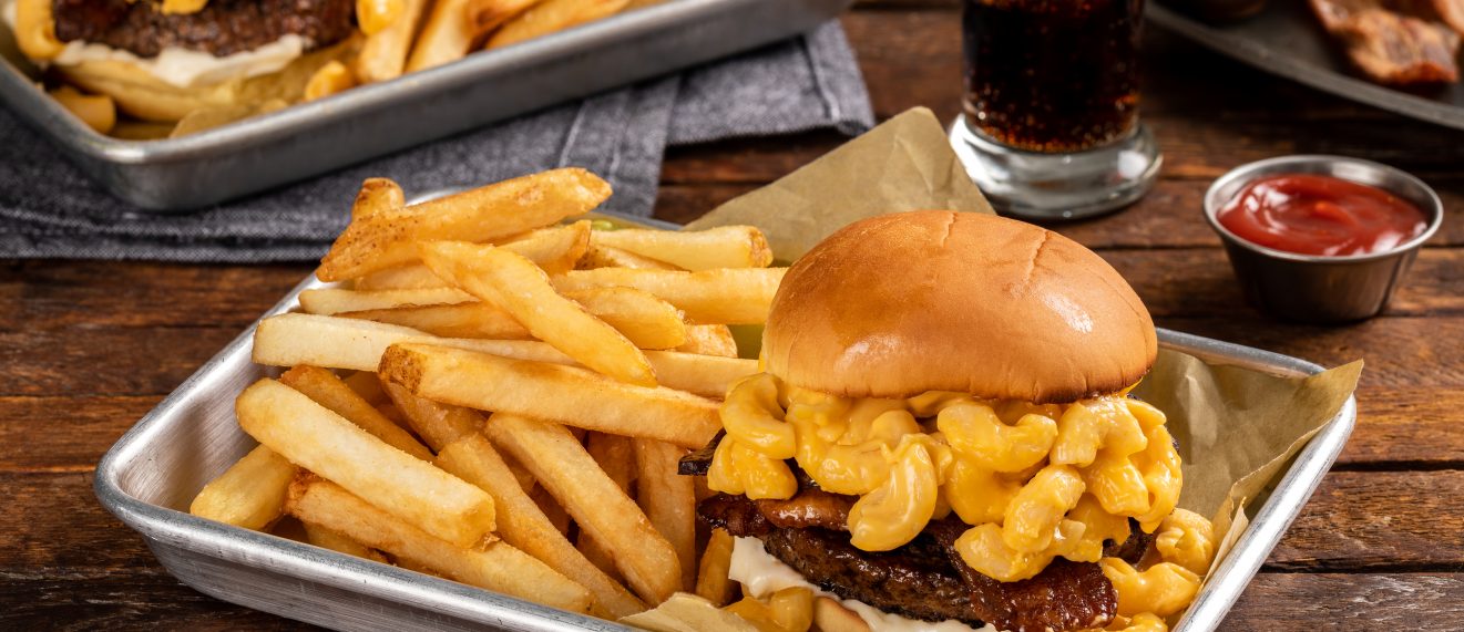 burger topped with mac and cheese and French fries on the side